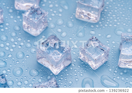 Close-up of ice placed against a blue background with water droplets spreading across it. Close-up of ice placed against a blue background with water droplets spreading across it. 139236922