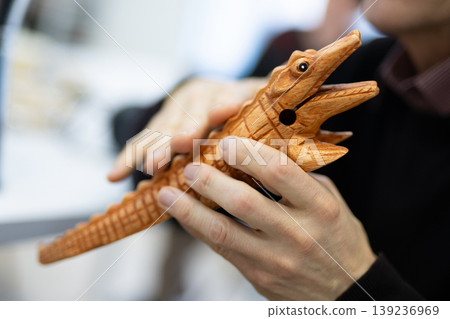 Person holding a handcrafted wooden crocodile guiro 139236969