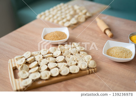 Homemade raw dumplings on a wooden board with bowls of grain Homemade raw dumplings on a wooden board with bowls of grain 139236978