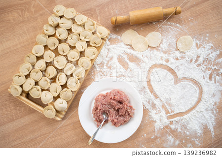 Top view of raw dumplings on board with meat filling and heart in flour 139236982