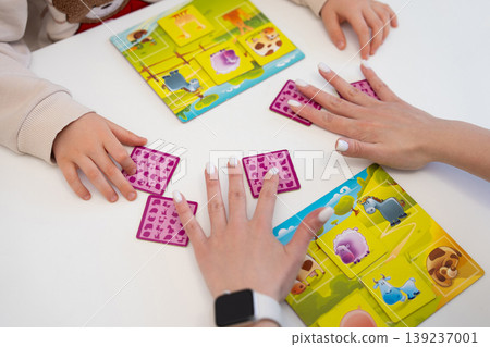 Top-down view of a child and woman playing a farm animal matching game Top-down view of a child and woman playing a farm animal matching game 139237001
