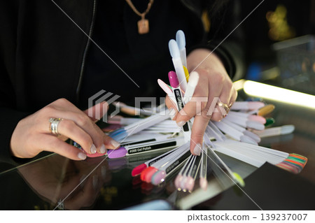 Manicurist showing a variety of nail polish color samples 139237007