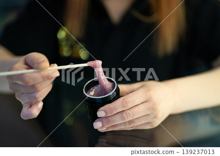 Manicurist using a wooden stick to lift glittery purple gel polish Manicurist using a wooden stick to lift glittery purple gel polish 139237013