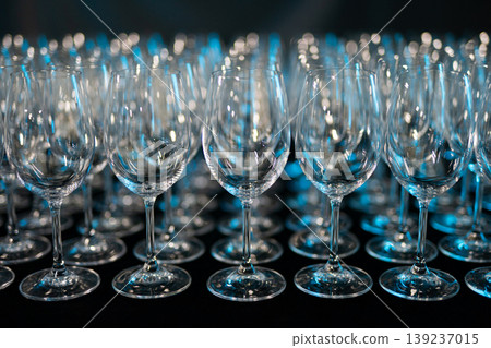 Rows of empty wine glasses on a dark background with blue lighting Rows of empty wine glasses on a dark background with blue lighting 139237015
