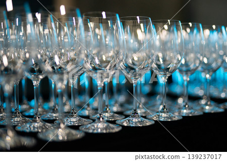 Rows of empty wine glasses on a dark background with blue lighting Rows of empty wine glasses on a dark background with blue lighting 139237017