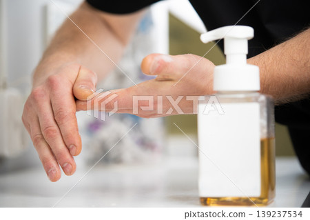 applying and rubbing the cosmetic product from the bottle into the hand 139237534