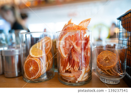 Dried citrus slices in glass jars on a bar counter Dried citrus slices in glass jars on a bar counter 139237541