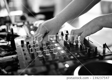 Black and white close-up of DJ hands mixing music on professional equipment 139237547
