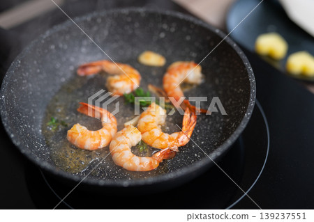 Sizzling shrimp with garlic and fresh herbs in a frying pan Sizzling shrimp with garlic and fresh herbs in a frying pan 139237551
