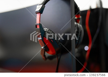 Red and black gaming headphones hanging on a monitor 139237566