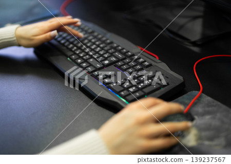 Woman's hands using a gaming keyboard and mouse Woman's hands using a gaming keyboard and mouse 139237567
