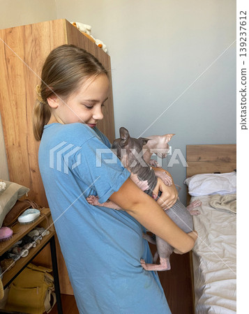 Cheerful child with cat pet indoors. Girl 10 years old and hairless kitten Cheerful child with cat pet indoors. Girl 10 years old and hairless kitten 139237612