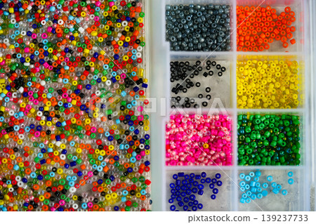 Close up of colorful seed beads in square sections pink shades, flat lay Close up of colorful seed beads in square sections pink shades, flat lay 139237733