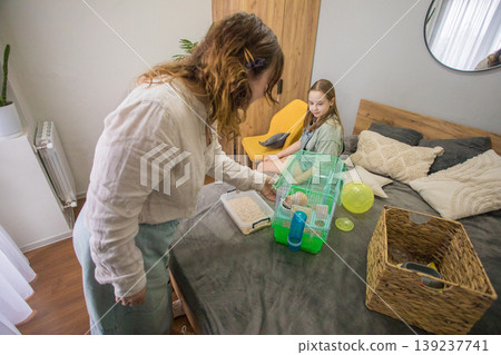 young girl and an adult are in a bedroom preparing a hamster cage 139237741