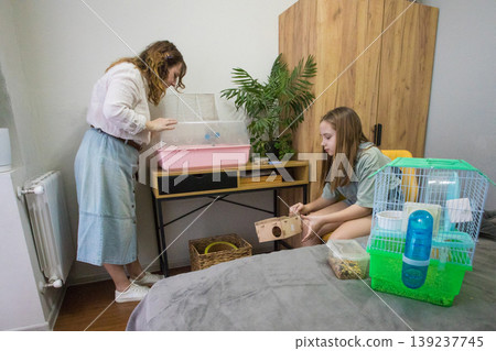 Two people are cleaning a hamster cage. Two people are cleaning a hamster cage. 139237745