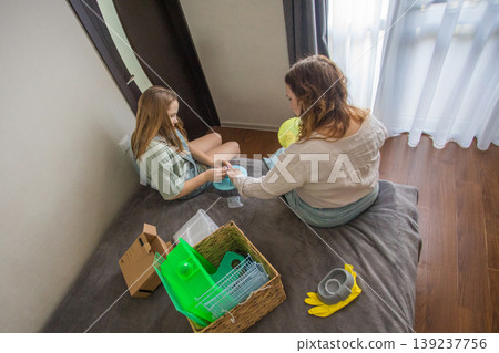 In a room with natural light, two girls work on putting together a pet. One girl holds a green ball 139237756