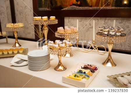Elegant dessert buffet with assorted gourmet sweets on gold stands 139237830