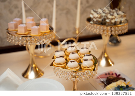 Assorted miniature mousse cakes on ornate gold serving stands 139237831