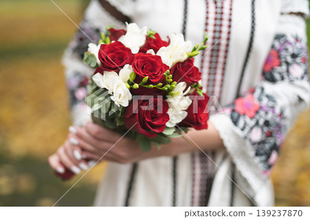 the bride and groom are holding hands with a bouquet of flowers and in traditional Ukrainian clothes the bride and groom are holding hands with a bouquet of flowers and in traditional Ukrainian clothes 139237870