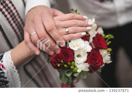 the bride and groom are holding hands with a bouquet of flowers and in traditional Ukrainian clothes the bride and groom are holding hands with a bouquet of flowers and in traditional Ukrainian clothes 139237871