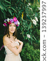 Close up portrait of a beautiful young girl with flower wreath in a sunny garden 139237997