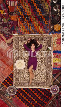 a beautiful girl in dress in a traditional turkish interior with many carpets on the wall 139238009
