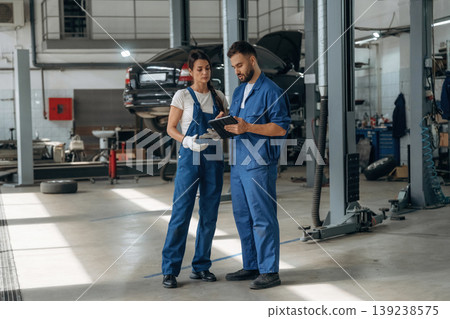 Data is in the digital tablet. Auto repair shop employees are working together. Man and woman Data is in the digital tablet. Auto repair shop employees are working together. Man and woman 139238575