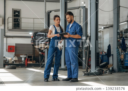 Data is in the digital tablet. Auto repair shop employees are working together. Man and woman Data is in the digital tablet. Auto repair shop employees are working together. Man and woman 139238576