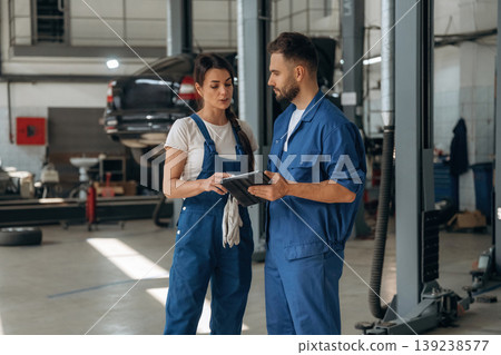 Data is in the digital tablet. Auto repair shop employees are working together. Man and woman Data is in the digital tablet. Auto repair shop employees are working together. Man and woman 139238577