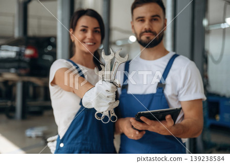 Showing the tools. Auto repair shop employees are working together. Man and woman Showing the tools. Auto repair shop employees are working together. Man and woman 139238584