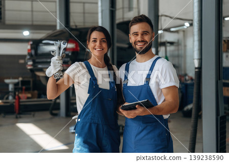 Tools in hand. Auto repair shop employees are working together. Man and woman 139238590