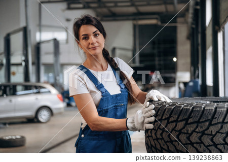 Taking a look at the tire. Female mechanic is working in the modern car workshop 139238863