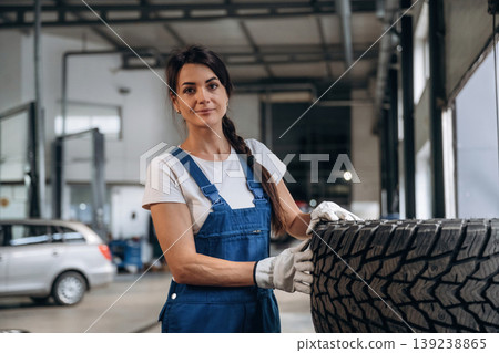Taking a look at the tire. Female mechanic is working in the modern car workshop 139238865