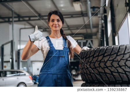 Smiling and showing thumb up. Female mechanic is working in the modern car workshop 139238867