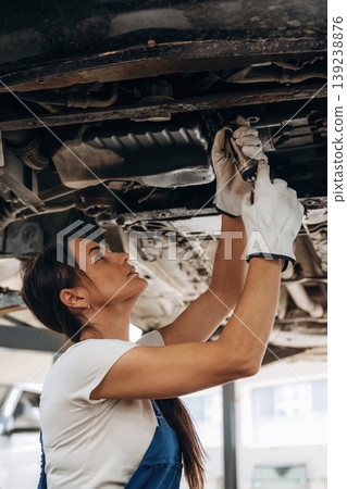 Under the automobile. Female mechanic is working in the modern car workshop 139238876