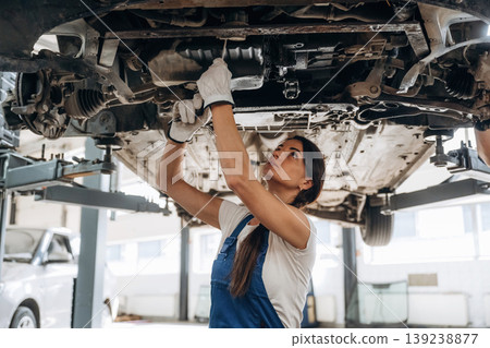 Under the automobile. Female mechanic is working in the modern car workshop 139238877