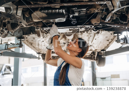 Under the automobile. Female mechanic is working in the modern car workshop Under the automobile. Female mechanic is working in the modern car workshop 139238878