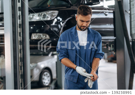 Protective gloves in hands. Male mechanic is working in the modern car workshop Protective gloves in hands. Male mechanic is working in the modern car workshop 139238991