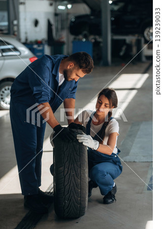 With tire. Auto repair shop employees are working together. Man and woman With tire. Auto repair shop employees are working together. Man and woman 139239033