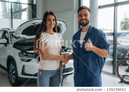 Deal, doing handshake. Woman customer is in the car repair service station with mechanic Deal, doing handshake. Woman customer is in the car repair service station with mechanic 139239042