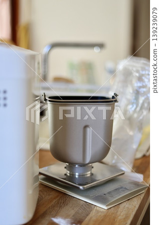 Bread pan of a home bread maker being weighed on a digital scale. Bread pan of a home bread maker being weighed on a digital scale. 139239079