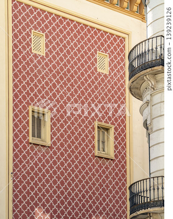 Ornate Red Patterned Facade With Decorative Windows and Iron Balcony in Historic Urban Building Ornate Red Patterned Facade With Decorative Windows and Iron Balcony in Historic Urban Building 139239126
