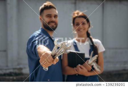 Cheerful male and female mechanics are standing outdoors together 139239201