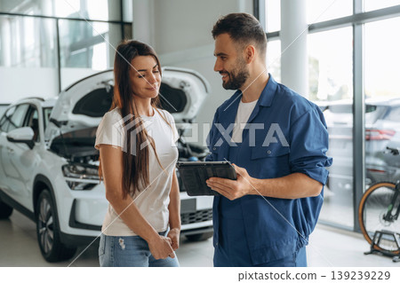 Giving the consultation. Woman customer is in the car repair service station with mechanic 139239229