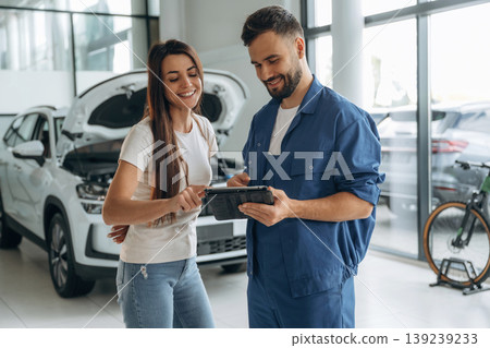 Woman customer is in the car repair service station with mechanic Woman customer is in the car repair service station with mechanic 139239233