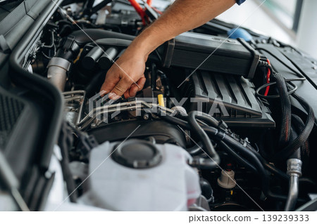 Fixing the car, hood is opened. Close up view of male service station worker at job Fixing the car, hood is opened. Close up view of male service station worker at job 139239333