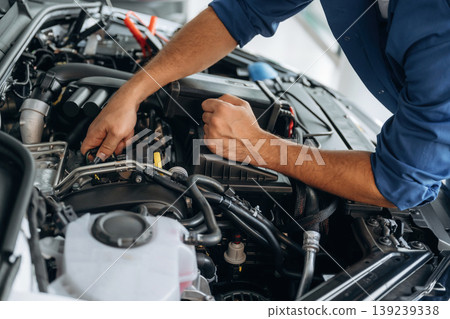 Hands visible only, hood is opened, fixing. Close up view of male service station worker at job Hands visible only, hood is opened, fixing. Close up view of male service station worker at job 139239338