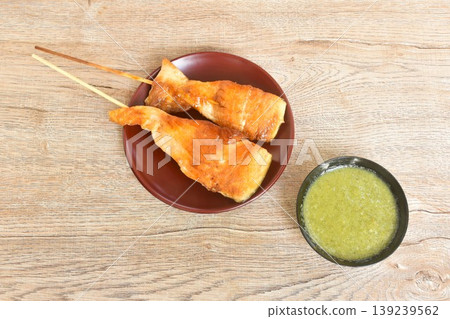grilled salmon dressing teriyaki sauce stabbing wooden stick on plate dipping spicy chili sauce grilled salmon dressing teriyaki sauce stabbing wooden stick on plate dipping spicy chili sauce 139239562