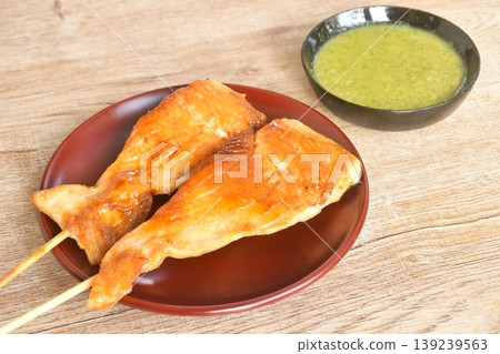grilled salmon dressing teriyaki sauce stabbing wooden stick on plate dipping spicy chili sauce grilled salmon dressing teriyaki sauce stabbing wooden stick on plate dipping spicy chili sauce 139239563