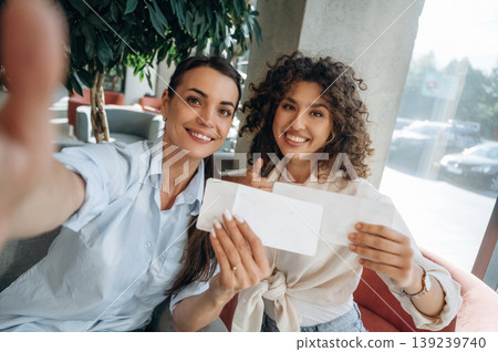 Doing selfie, tourists. Two women are indoors in the modern hall of building at daytime 139239740